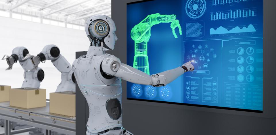 Robot standing in front of a large monitor manipulating and reviewing industrial robot arms that are positioned on tables to the side. 