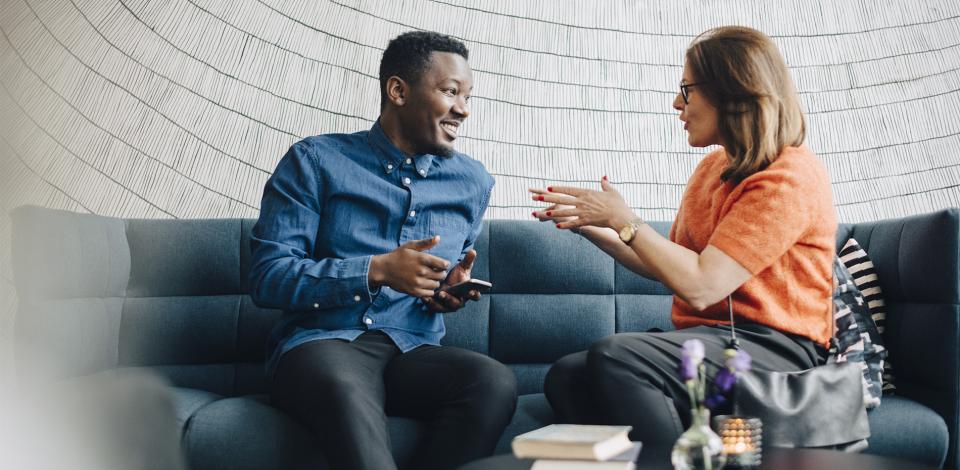 Man and women sitting on a couch in a relaxed position, deep in thoughtful conversation. 