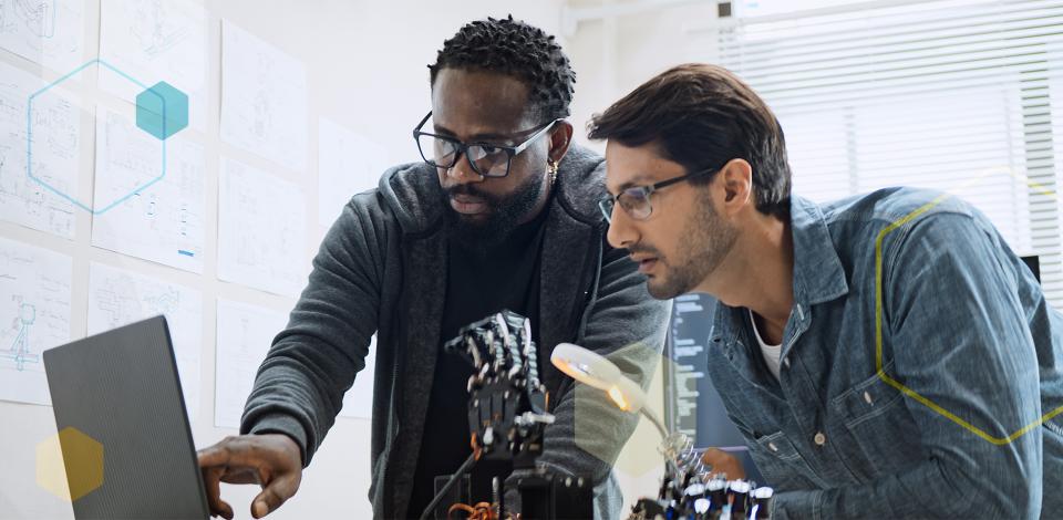 Two men working together on a robot hand.