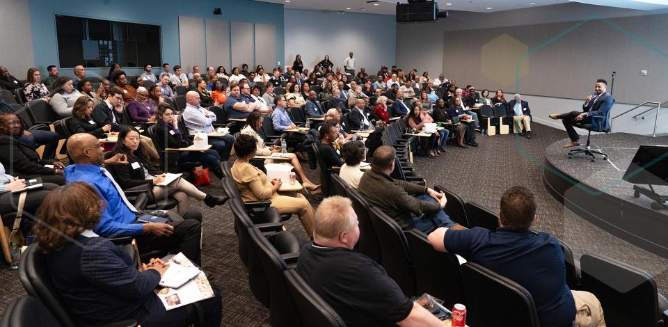 Large group of people listening to a speaker in a conference room.