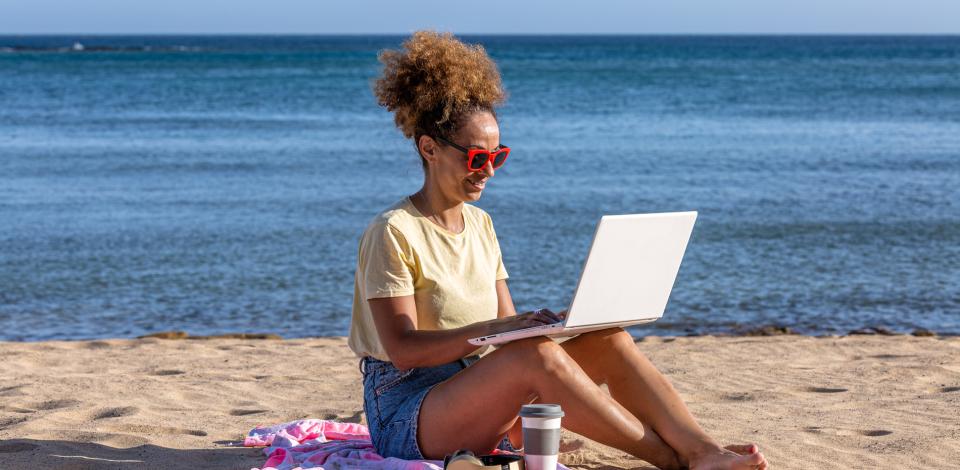 Woman sitting on the beach with laptop