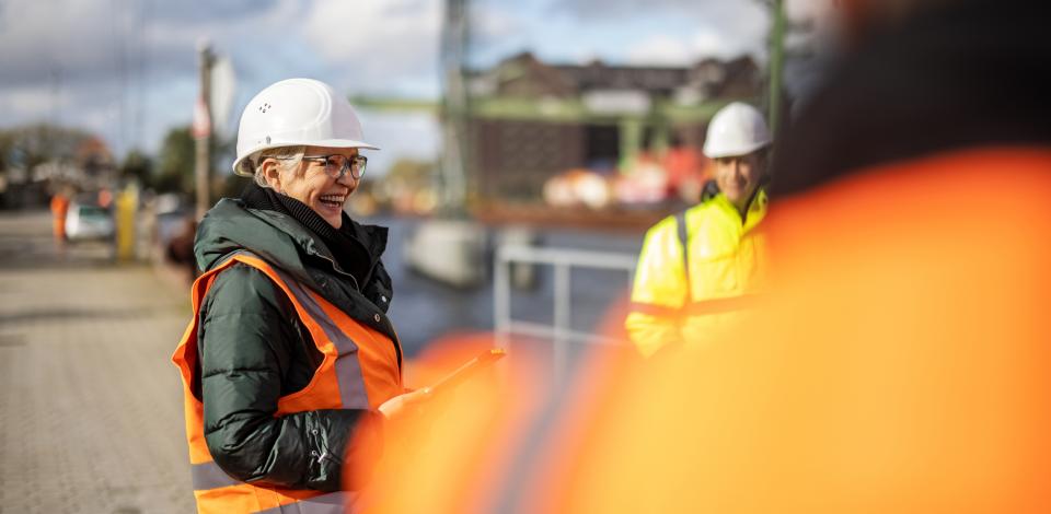 Female safety professional smiling while talking with other workers.