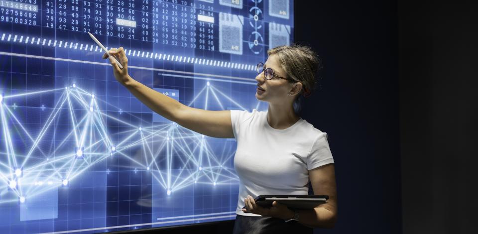 Woman standing in front of large screen discussing data