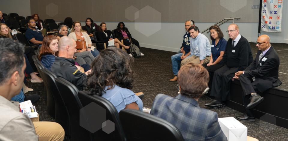 A panel of presenters speaking to an audience in an auditorium.
