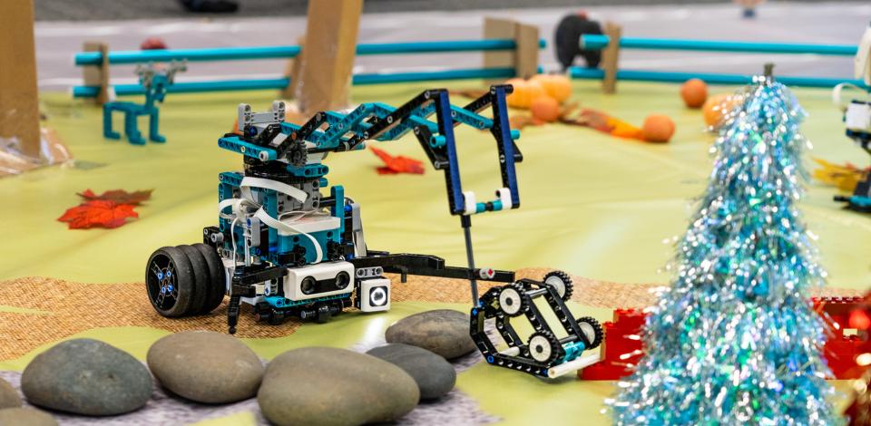 A small, student-built robot navigates a mock rescue course, moving around obstacles toward a designated target.