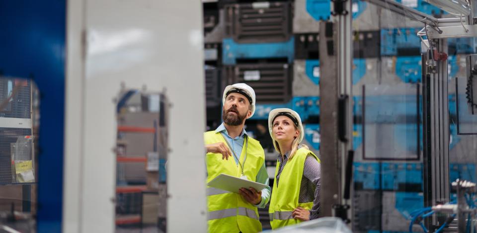 Male and female employees standing in a manufacturing plant.