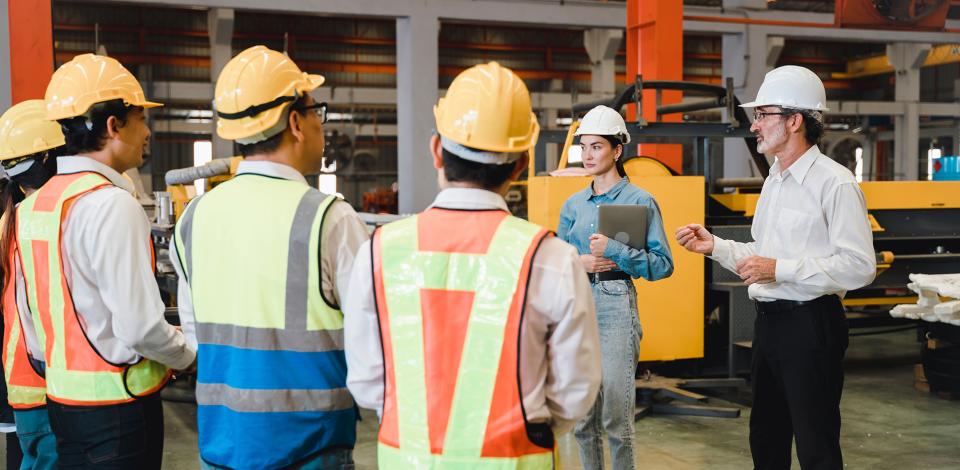 Two safety professionals briefing factory employees 