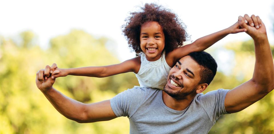 Smiling father and young daughter playing outdoors