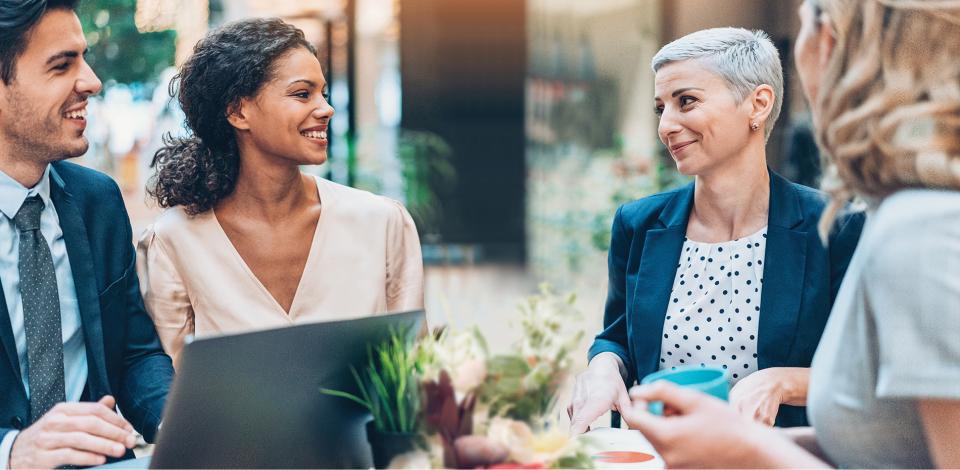 Four adult working professions of varying ages and genders sit around a conference table