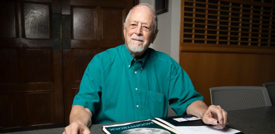 Bob Macdonald, online masters in analytics student, sits at table with historic moon landing documents in front of him.