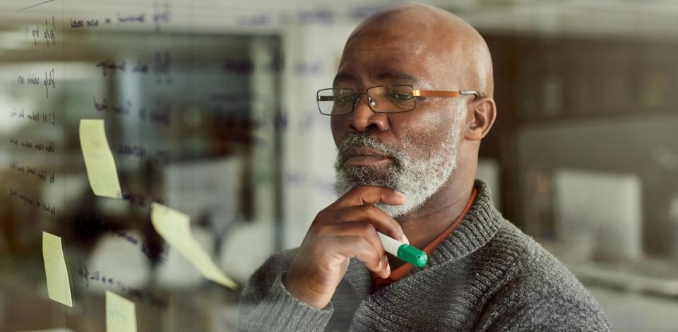 Cropped shot of a mature businessman brainstorming with notes on a glass wall