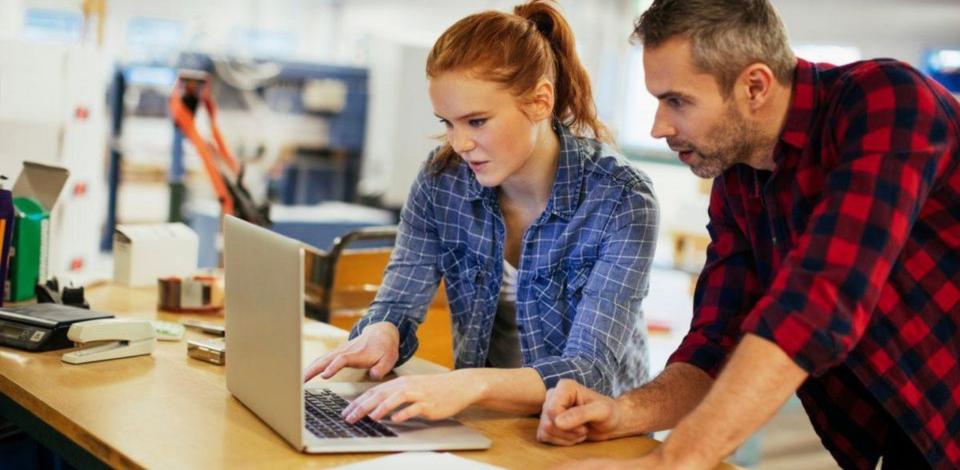 A female and male are collaborating over a laptop computer