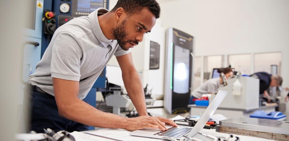 Male engineer using CAD programming software on laptop.