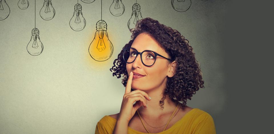 Woman looking inspired with light bulbs in background