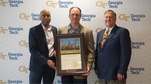 Men holding a framed tech tower picture and certificate
