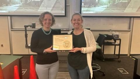 Two women holding framed OSHA certificate in front of Georgia Tech classroom.