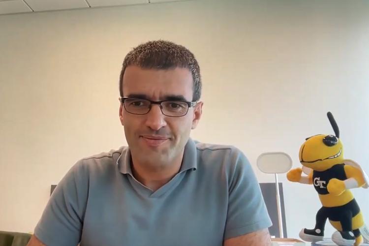 Saman speaking at cybersecurity panel with Buzz mascot in foreground