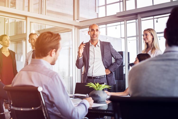 Male employee standing to address colleagues at a meeting