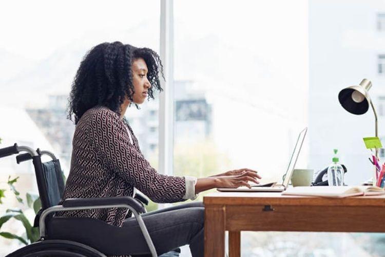 Female people leader in wheelchair taking online assessment on laptop