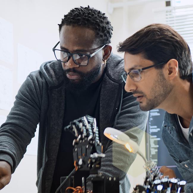 Two men working together on a robot hand.