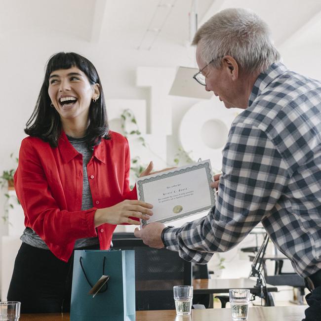 Employee receiving a certificate and being celebrated by colleagues