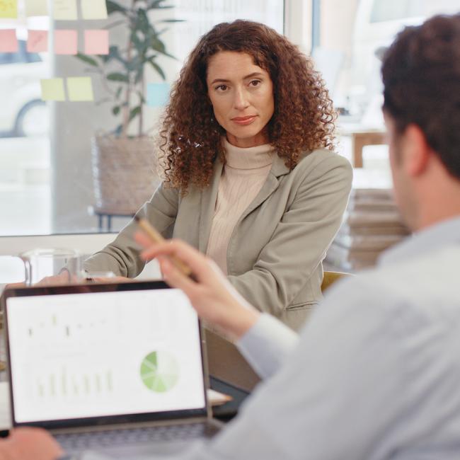 Four professionals sitting around a table discussing data on a laptop