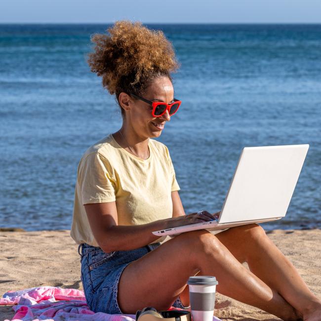Woman sitting on the beach with laptop