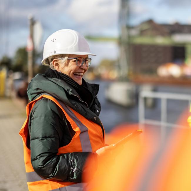 Female safety professional smiling while talking with other workers.