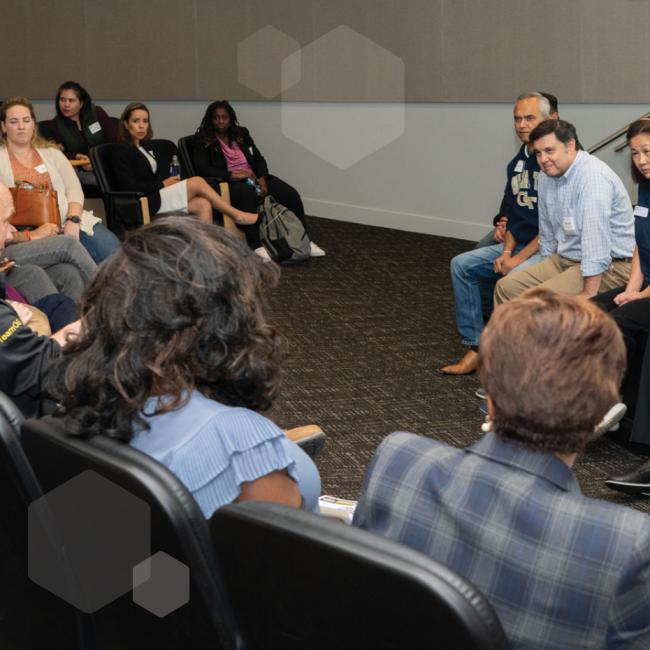 A panel of presenters speaking to an audience in an auditorium.