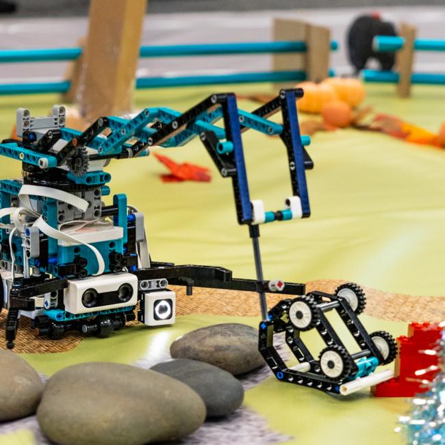 A small, student-built robot navigates a mock rescue course, moving around obstacles toward a designated target.