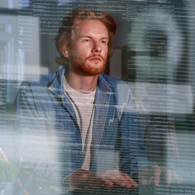 Man sitting at desk looking at floating lines of code and different charts meant to symbolize AI outputs
