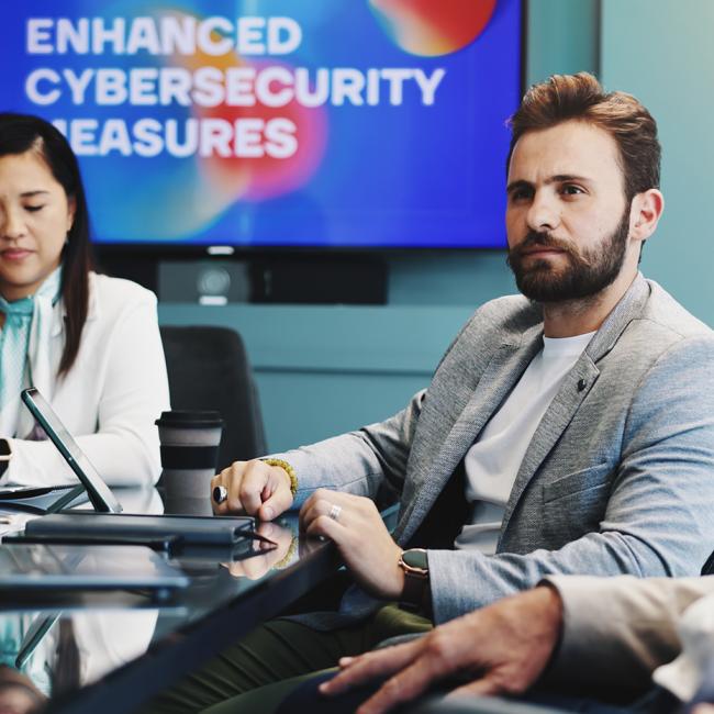 Three cybersecurity professionals sitting in a conference room giving a presentation on cybersecurity measures.