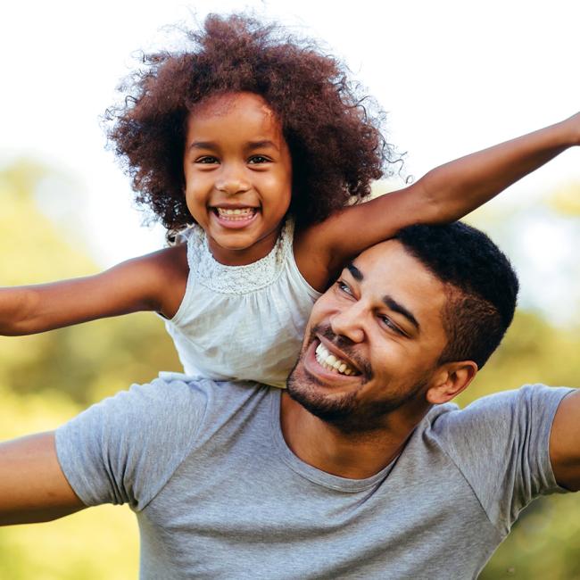 Smiling father and young daughter playing outdoors