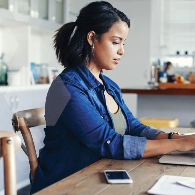 Remote worker using laptop computer and mobile phone to work from home.